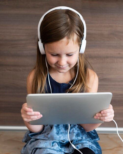 child wearing headphones holding tablet 